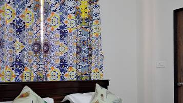 Una habitación de hotel con cama, almohadas y cortina con diseño colorido.