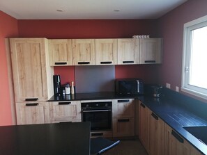 A kitchen with wooden cabinets, a microwave, a coffee maker, and a window.