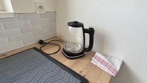 Un piano di lavoro in cucina con una macchina per il caffè, un cavo di alimentazione e un asciugamano.