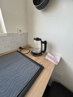 Una encimera de cocina con una cafetera, un cable de alimentación y una toalla.