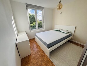 Une chambre à coucher avec un lit, une fenêtre, un bureau et un luminaire.