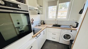Una cucina compatta con forno integrato, lavatrice e finestra.