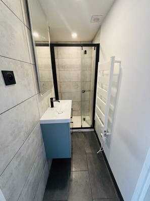 Une salle de bain moderne avec une douche à parois de verre, un lavabo blanc et un porte-serviettes.