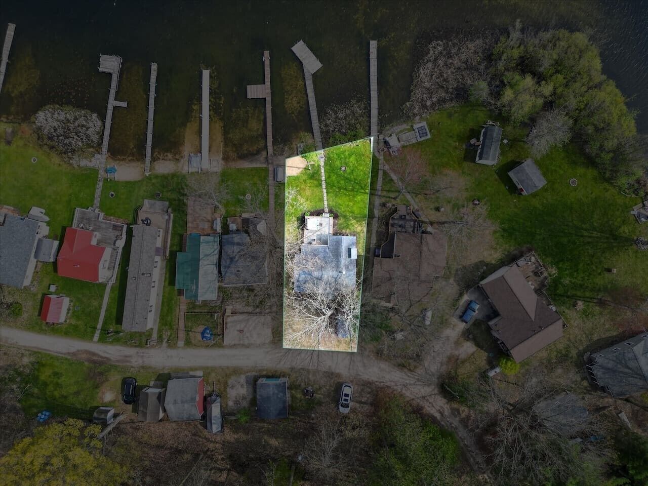 Vista aérea de una zona residencial con casas, un muelle y un campo cubierto de césped.