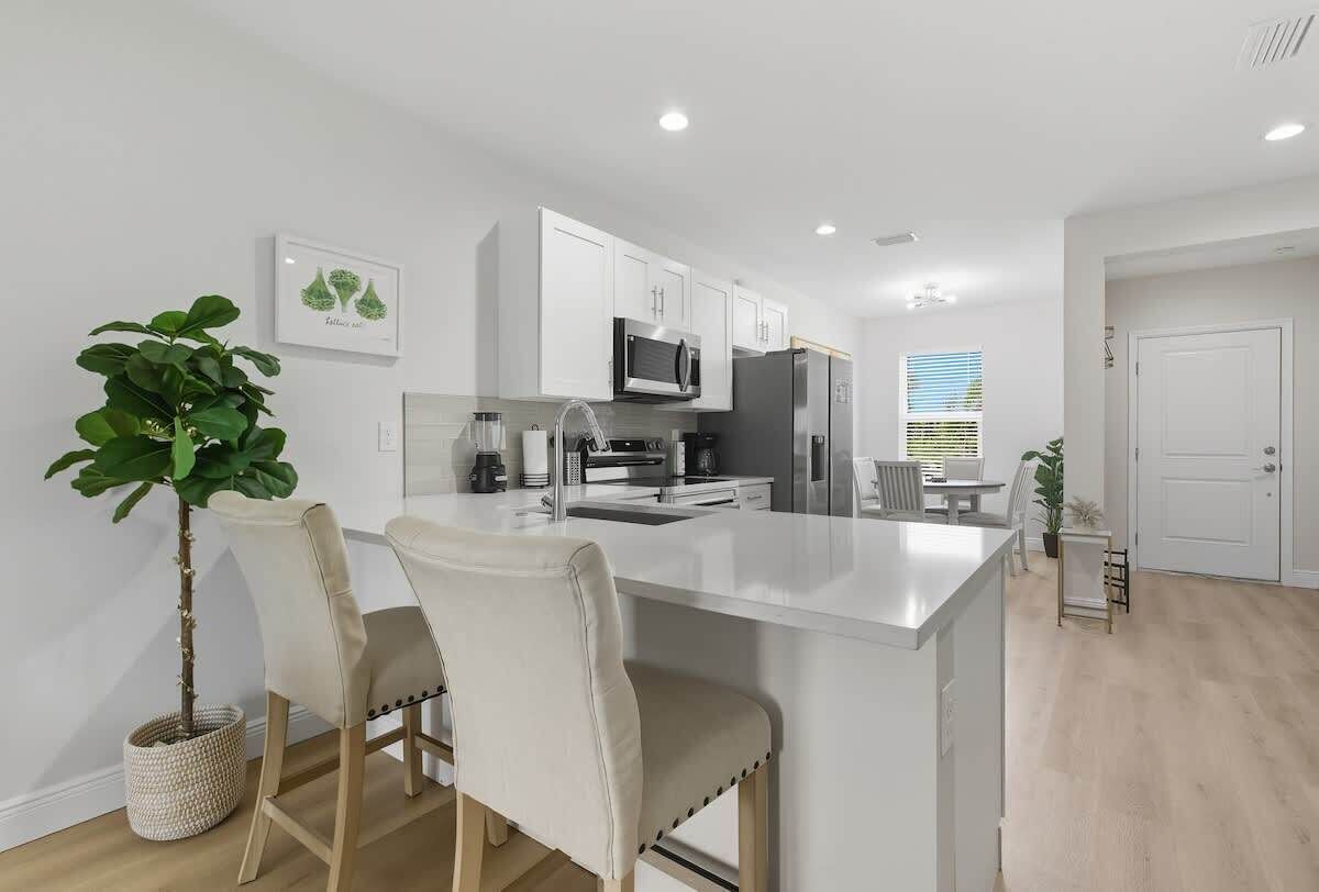 A modern kitchen with white cabinetry, a central island, and bar stools.