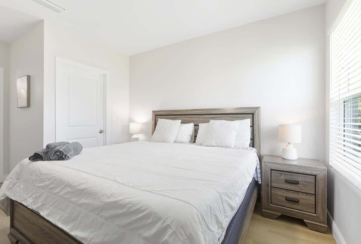 A bedroom with a bed, bedside tables, and a window.