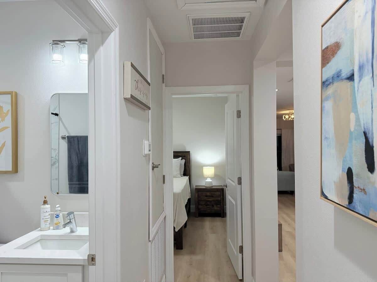 A hallway leading to a bedroom with a bedside table, a lamp, and a bed.