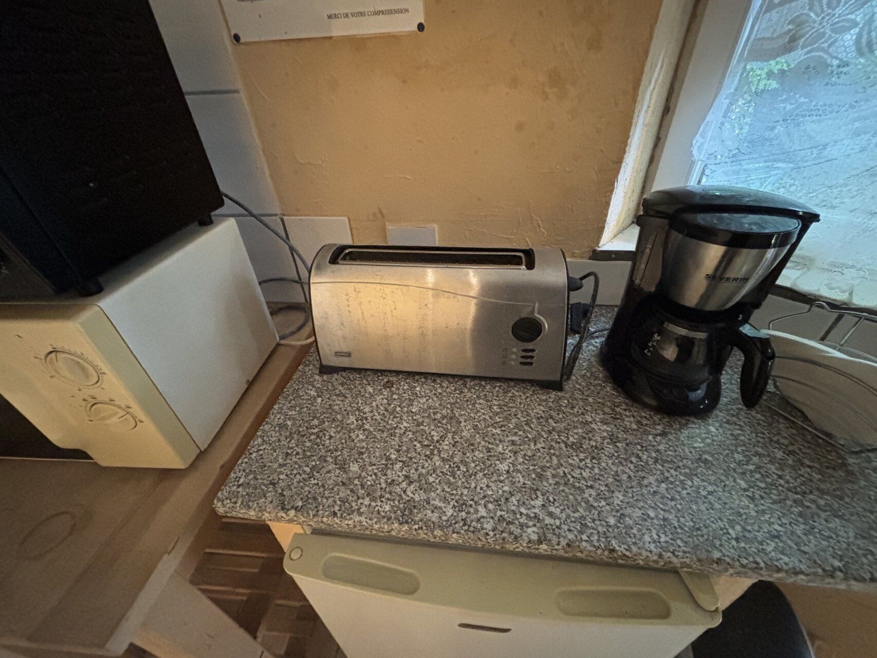 A kitchen with a toaster, a coffee maker, and a window.