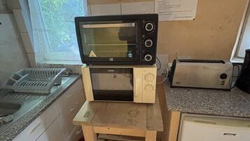 Een kleine keuken met een magnetron, broodrooster en een koelkastje.