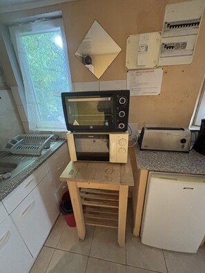 A compact kitchen with a microwave, toaster, and a small refrigerator.