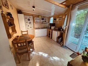 A compact kitchen with a dining table, chairs, a refrigerator, and a sink. - The 4th of the Cressonnière (Agny)
