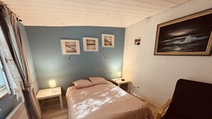 A bedroom with a bed, bedside tables, a lamp, a painting, and a window with curtains.