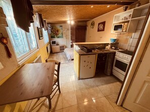 Una cucina compatta con zona pranzo, forno a microonde e piano cottura.