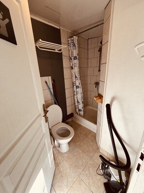 Un bagno compatto con il water, la doccia e un porta asciugamani.