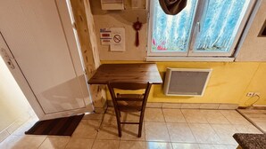 A kitchen with a wooden table, a window with a view, a vent, and a door.
