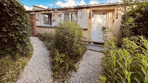 A small building with a gravel path, surrounded by greenery and a clear sky.