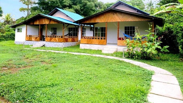 A two-story house with a porch, a pathway leading to the entrance, and a lush green lawn.