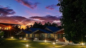 A resort with multiple bungalow-style buildings, a well-maintained lawn, and a sunset sky.