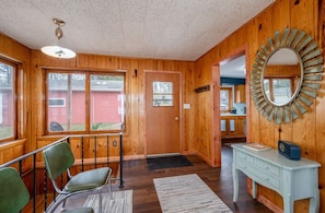 A wooden interior with a door, a mirror, a desk, and a chair.