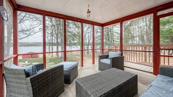 Un espace extérieur aménagé, abrité et doté de mobilier en osier, offrant une vue sur un lac.