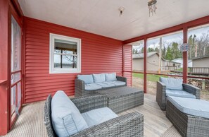 A covered outdoor seating area with wicker furniture and a red exterior wall.