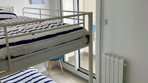 A room with two bunk beds, a radiator, a window, and a door. - Waterfront apartment| Towels and sheets (Saint-Gilles-Croix-de-Vie)
