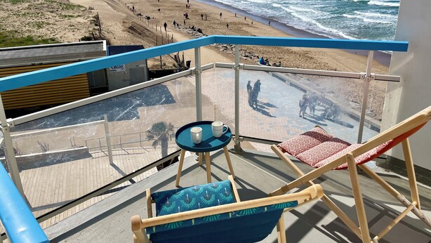 A balcony with a view of the beach, a chair, a table, and a railing. - Waterfront apartment| Towels and sheets (Saint-Gilles-Croix-de-Vie)
