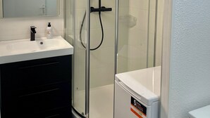 A modern bathroom with a glass-enclosed shower, a white sink, and a compact toilet. - Waterfront apartment| Towels and sheets (Saint-Gilles-Croix-de-Vie)