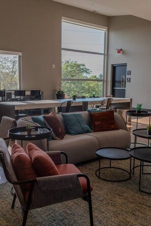 A modern living room with a sofa, chairs, a coffee table, and a view through large windows. - Sipped Away: King Beds, Walk in Closets (Traverse City)