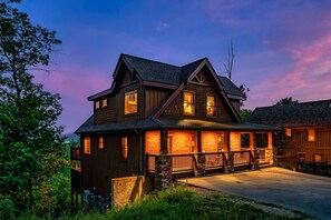 Ein zweistöckiges Holzhaus mit Steinuntergrund, einer Veranda mit Geländern und zahlreichen Fenstern.