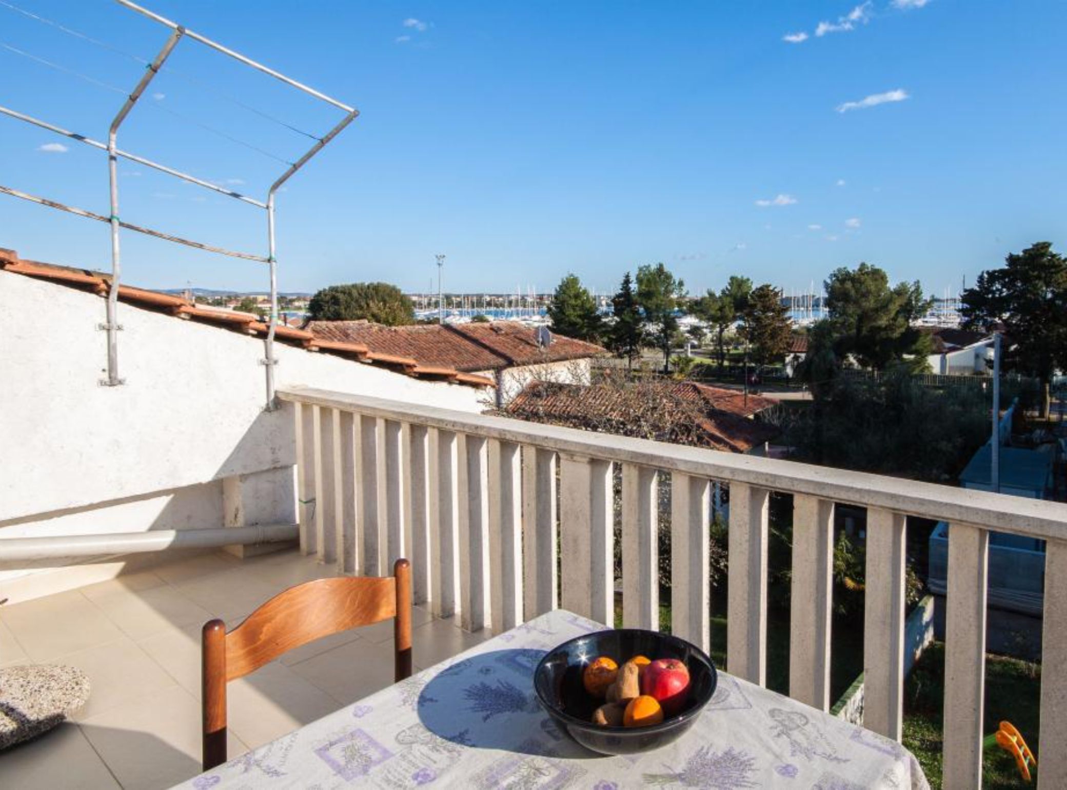 Ein Balkon mit Tisch, einer Obstschale und einem Stuhl.