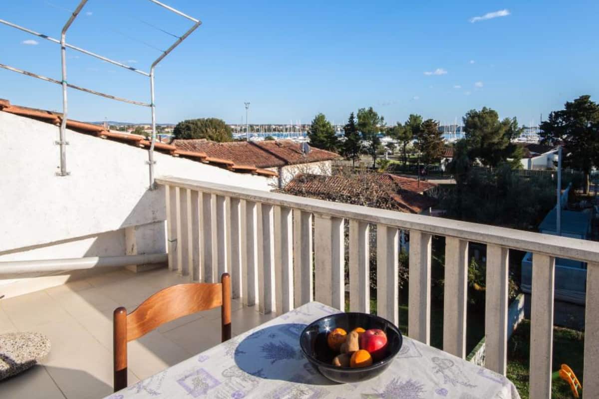 Un balcon avec une table, un panier de fruits et une chaise.
