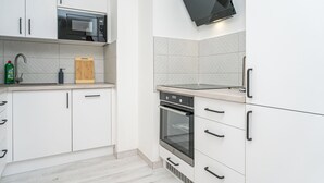 Eine moderne Küche mit weißen Schränken, einer Mikrowelle, einem Backofen und einem integrierten Fernseher.