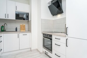 Eine moderne Küche mit weißen Schränken, einer Mikrowelle, einem Backofen und einem integrierten Fernseher.