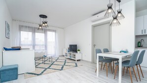Ein modernes Wohnzimmer mit Essbereich, weißen Wänden und einem großen Fenster.