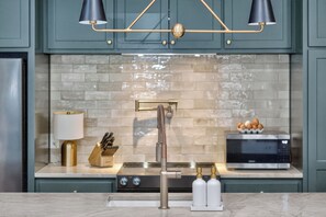 A kitchen with teal cabinets, a marble countertop, a stainless steel range, a microwave, a sink with a modern faucet, and pendant lighting. - Stylish Farmstay on 6 Acres • Cowboy Pool • Fresh Eggs • Casita • Fire Pit (Tyler)