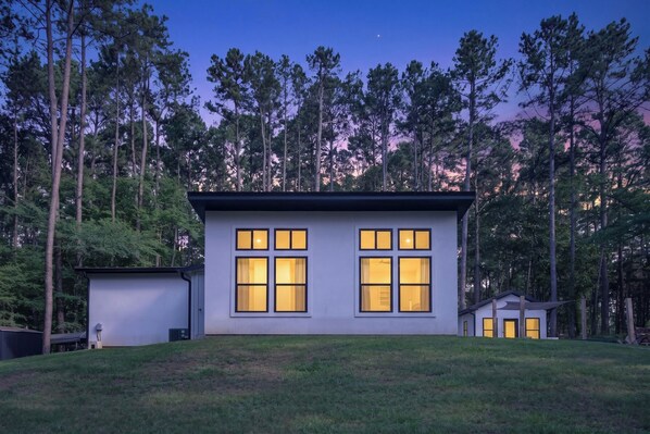 A modern house with large windows, surrounded by a forest. - Stylish Farmstay on 6 Acres • Cowboy Pool • Fresh Eggs • Casita • Fire Pit (Tyler)