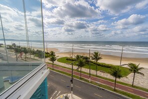 Blick auf die Küste von einem Hochhaus aus, mit einer Straße, Palmen und einem Strand.