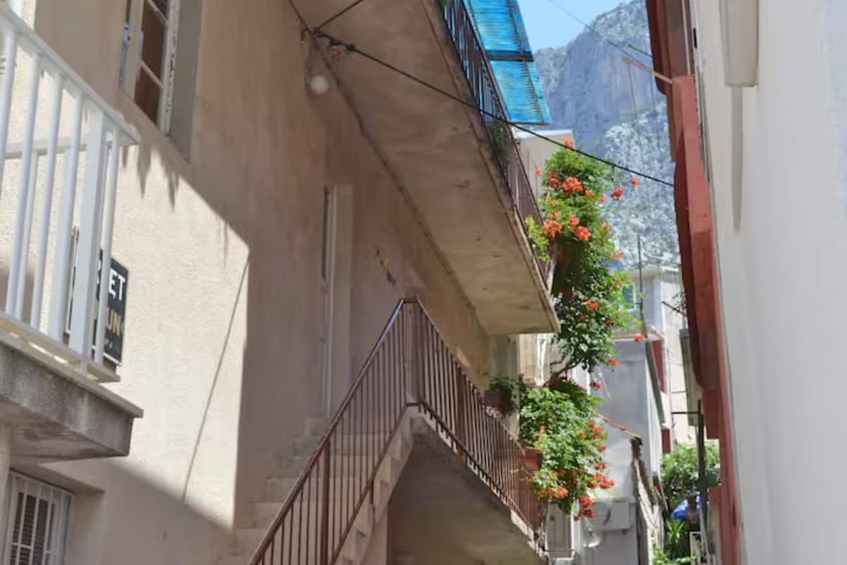 Un edificio con balcón, escaleras y una montaña al fondo.