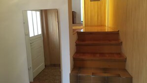 Una escalera con peldaños de madera y un rellano de baldosas.