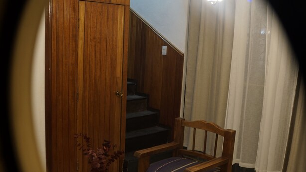 A wooden staircase leading to a landing with a wooden door, a wooden chair with a cushion, and a small table with a vase. - Arrona" Department (Oaxaca de Juárez)