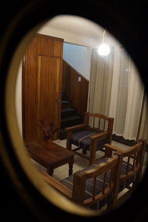 A wooden staircase leading to a landing with a wooden door, a wooden chair with a cushion, and a small table with a vase. - Arrona" Department (Oaxaca de Juárez)