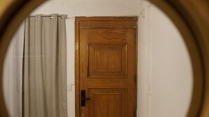A circular window view of a wooden door, a curtain, and a small object on the floor. - Arrona" Department (Oaxaca de Juárez)