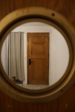 A circular window view of a wooden door, a curtain, and a small object on the floor. - Arrona" Department (Oaxaca de Juárez)
