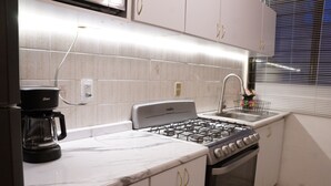 A kitchen with white cabinets, a gas stove, a coffee maker, and a sink. - Arrona" Department (Oaxaca de Juárez)