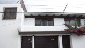 A two-story building with a white facade, two dark brown doors, and a small window with a mesh screen. - Arrona" Department (Oaxaca de Juárez)
