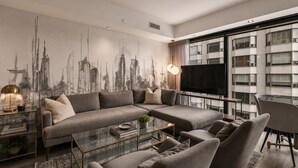 Una sala de estar moderna con un sofá modular, una mesa de centro de vidrio y un televisor grande.