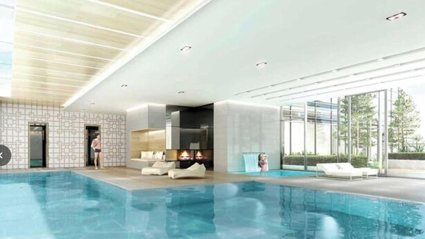 Una piscina interior moderna con una chimenea, sillones de descanso y vistas a zonas verdes.