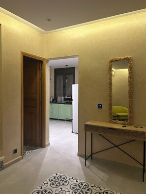 A hallway with a wooden door, a console table with a mirror, and a patterned rug.