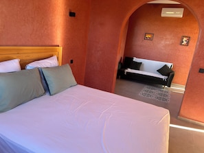 A hotel room with a bed, a sofa, and a small table.